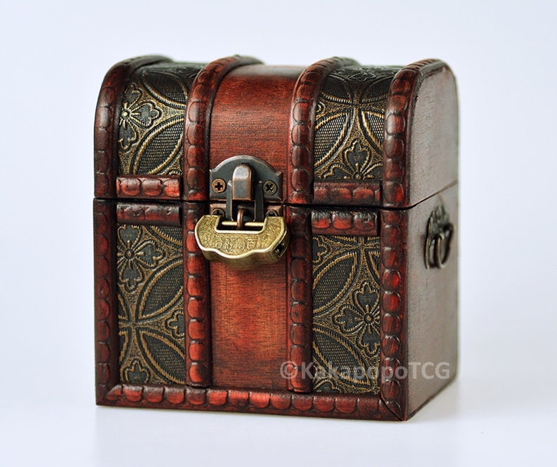 May include: A small wooden treasure chest with a brass lock and hinges. The chest is decorated with a gold and brown patterned design.