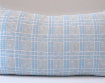 May include: A rectangular decorative pillow with a light blue and white plaid pattern. The pillow has a soft, textured appearance and is designed for home decor. The plaid design features a grid of light blue and white lines.
