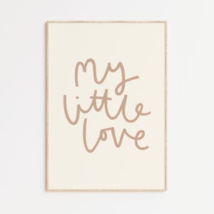 May include: A beige framed print with the text "my little love" in a brown cursive font.