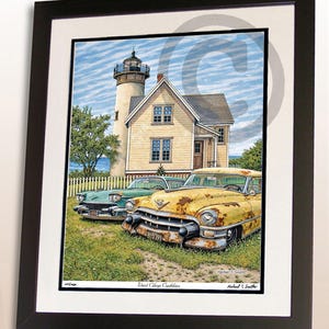 May include: Framed print featuring a lighthouse and a yellow house with two classic cars parked in front. The cars are a teal green and a rusty yellow. The print is titled "West Chop Caddies".