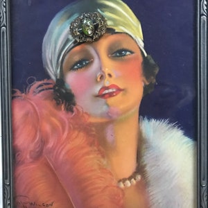 Puede incluir: Un retrato enmarcado de una mujer con un turbante blanco con un broche de joyas, un boa de plumas rosa y un cuello de piel blanca. La mujer tiene el pelo oscuro y mira hacia arriba. El retrato est&aacute; firmado "Wilson" en la esquina inferior izquierda.