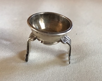 May include: A silver salt cellar with a round bowl and three legs.