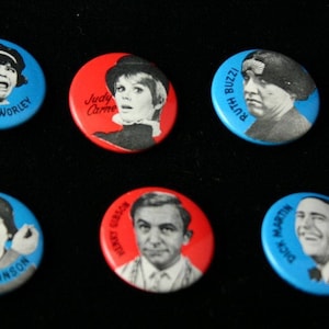 May include: Six round blue and red buttons with white lettering and images of people's faces. The buttons feature the names "Joanne Worley", "Judy Carne", "Ruth Buzzi", "Dick Martin", "Arte Johnson", and "Harvey Korman".