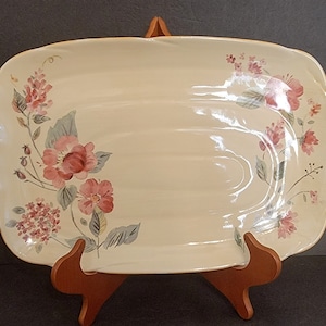 May include: A white ceramic serving platter with a floral design. The platter has a scalloped edge and features pink and green flowers.