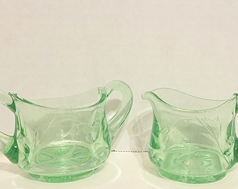 May include: A set of two vintage green glass creamer and sugar bowl with etched floral designs.