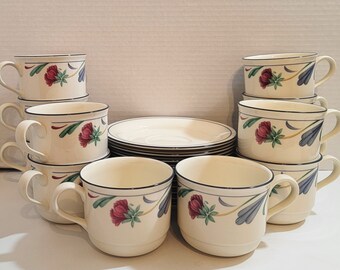 May include: A set of 10 white teacups and saucers with a floral design featuring red, green, and blue accents. The cups and saucers are stacked in two piles of five.