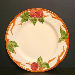 May include: A white ceramic dinner plate with a brown rim and a hand-painted design of red apples, green leaves, and brown branches.