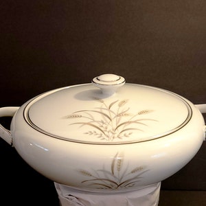 May include: White ceramic serving bowl with a lid and two handles. The bowl has a gold trim and a wheat design in brown and gray.