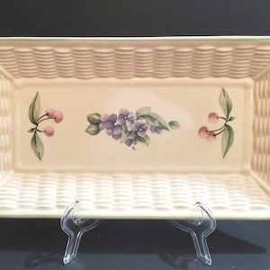 May include: A rectangular ceramic serving dish with a woven basket design. The dish is decorated with a floral motif and two cherries on each side.
