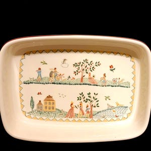 May include: Cream-coloured rectangular serving dish with a red rim. The dish showcases a detailed pastoral scene with figures, trees, and houses, framed by a yellow and green zigzag border. The design is reminiscent of vintage tableware.