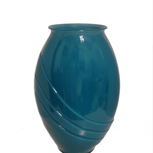 May include: A teal blue ceramic vase with a rounded, oval shape and a swirling design. The vase is glossy and has a smooth finish.
