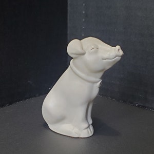 May include: A white ceramic pig figurine with a closed eye and a slight smile. The pig is sitting with its legs tucked under its body.