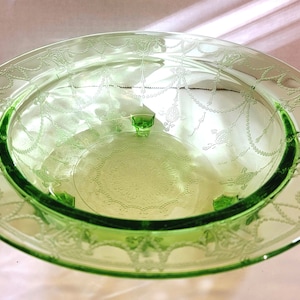 Könnte beinhalten: Eine grüne Glasschüssel mit einem geätzten Design aus einer Girlande von Blumen und Blättern. Die Schüssel hat drei Füße und ist in ausgezeichnetem Zustand.