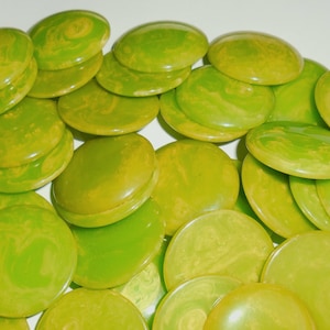 May include: A collection of round, flat buttons featuring a marbled pattern of lime green and yellow. Each button has a smooth, glossy finish with a slightly domed surface, creating a vibrant and cohesive display of circular shapes in various shades.