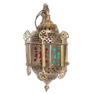 May include: A brass lantern with a decorative, openwork design and colorful glass panels. The lantern has a hanging loop and a pointed finial at the bottom.