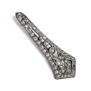 May include: A silver-toned brooch with a geometric design, encrusted with numerous clear, sparkling rhinestones. The brooch has a long, slender shape with a pointed end and a series of larger, round stones. A classic piece of jewelry.
