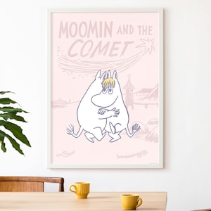 May include: A framed poster with the text "MOOMIN AND THE COMET" in pink. The image shows a Moomin character hugging another, set against a light pink background with illustrations of a comet and a landscape.