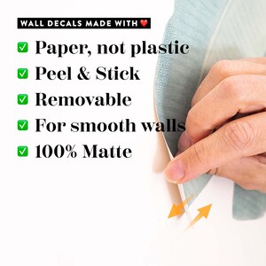 May include: A close-up of a hand peeling back a green and white wall decal. The decal is made of paper, not plastic, and is peel and stick, removable, for smooth walls, and 100% matte.