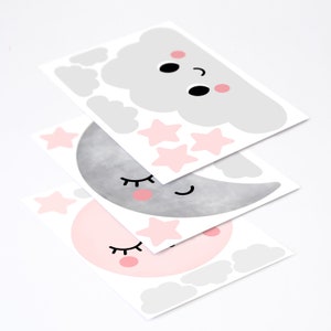 May include: Three sheets of wall decals featuring a pink and gray moon, a pink moon, and a gray cloud with pink cheeks. Each decal has a smiling face with closed eyes and eyelashes. The cloud decal also has three pink stars.