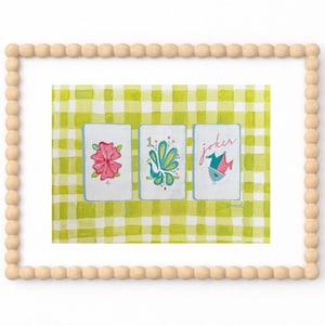 Puede incluir: Una impresi&oacute;n art&iacute;stica enmarcada que presenta tres naipes con ilustraciones florales y de aves sobre un fondo a cuadros verde y blanco. El marco est&aacute; hecho de cuentas de madera de color claro.