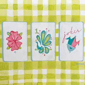 Puede incluir: Tres naipes ilustradas. La primera carta presenta una flor rosa y el n&uacute;mero 4. La segunda carta tiene un dise&ntilde;o turquesa y amarillo con el n&uacute;mero 1. La tercera carta dice "joker" y tiene un p&aacute;jaro con un gorro de buf&oacute;n.