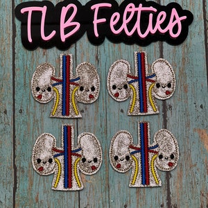 May include: Four felt kidney patches with a cute cartoon face and glitter. The kidneys are red, blue, and yellow. The text "TLB Felties" is on a black background with pink lettering.