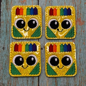May include: Four yellow felt crayon box patches with a rainbow of crayons on top and a smiling face with big eyes.
