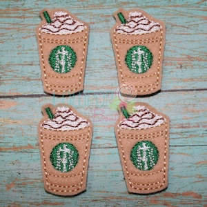 May include: Four brown and green embroidered patches of iced coffee drinks with whipped cream and a straw.