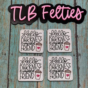 May include: Four white felt squares with the text "Hello Darkness my old friend" and a coffee cup graphic. The text is in black and the coffee cup is brown with a pink heart.