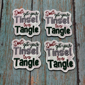 May include: Four white iron-on patches with the text "Don't get your Tinsel in a Tangle" in red, green, and silver glitter lettering.
