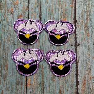 May include: Four iridescent purple and white iron-on patches featuring a cartoon character with a purple and white hat and a black face. The character has a yellow star on their chest.