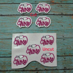 May include: A sheet of white fabric with six pink and silver embroidered patches that say "Nurse" with a stethoscope design. The patches are arranged in two rows of three. The top row is labeled "Cut" and the bottom row is labeled "Uncut".