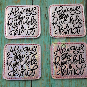 May include: Four square patches with rounded corners featuring a holographic silver finish. Each patch has black embroidered cursive text that reads Always stay humble & kind, surrounded by a pink stitched border along the outer edge.