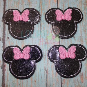 May include: Four black and pink glitter iron-on patches featuring a cartoon mouse head with a bow.