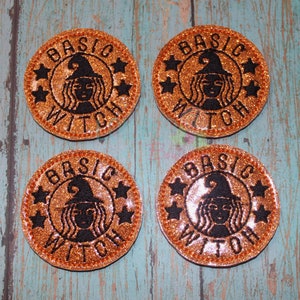 May include: Four round orange glitter patches with black embroidery. Each patch features a witch with a pointed hat, the text "BASIC WITCH" and three stars.