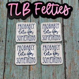 May include: Four white felt squares with the text "PROBABLY late for SOMETHING" embroidered in blue thread. The squares are arranged in two rows of two. The text "TLB Felties" is written in pink letters on a black background.