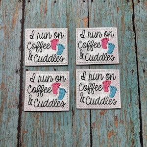 May include: Four white square patches with the text "I run on Coffee & Cuddles" and a pink and blue footprint design.