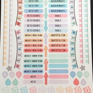 Pu&ograve; includere: Un foglio di adesivi colorati con vari disegni e testi. Gli adesivi sono organizzati in righe e colonne. Il testo sugli adesivi include "Keto Tips", "Achievements", "Goals", "Weekly-Meal-Plan", "Grateful For", "Weekly-Snack-Plan" e "Keto".