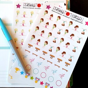 May include: Two sheets of stickers featuring a gymnast in various poses. The stickers are on a white background with pink, blue, green, yellow, and gold accents. The stickers are from Lilly Top Stickers and Stationary. The text "Lilly Top" is on the bottom right corner of the sheet.
