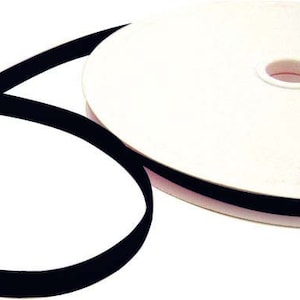 Könnte beinhalten: Eine Rolle schwarzes Klettband, auch bekannt als Velcro, auf einer weißen Unterlage. Das Band ist abgewickelt und gefaltet dargestellt.