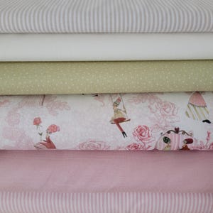 Könnte beinhalten: Ein Stapel verschiedener Stoffmuster in Weiß-, Rosa- und Grüntönen. Die Stoffe umfassen Streifen, Punkte und ein Blumenmuster mit skurrilen Illustrationen. Geeignet für Näh- und Bastelprojekte.