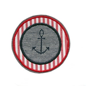 Könnte beinhalten: Ein roter und weißer gestreifter Stoffkreis mit einem dunkelblauen Anker in der Mitte.