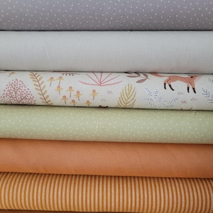 Könnte beinhalten: Ein Stapel Stoffrollen in verschiedenen Farben und Mustern. Die oberste Rolle ist grau mit weißen Punkten, gefolgt von einem einfarbigen Off-White, einer cremefarbenen Rolle mit einem Fuchs- und Blumendesign, einem hellgrünen Punkt, einem einfarbigen Orange und einem gestreiften orangefarbenen Stoff.