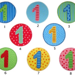 Könnte beinhalten: Acht bunte Filz-Kreise mit einer Nummer eins in der Mitte. Jeder Kreis hat ein anderes Muster: blau mit grünen Streifen, blau mit weißen Punkten, grün mit blauen Streifen, rot mit weißen Punkten, blau mit orangefarbenen Streifen, gelb mit orangefarbenen Punkten, grün mit roten Punkten und rosa mit grünen Streifen.