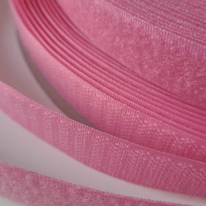 Könnte beinhalten: Nahaufnahme von rosa Klettband, auch bekannt als Velcro, aufgerollt. Das Band ist weich und flauschig.
