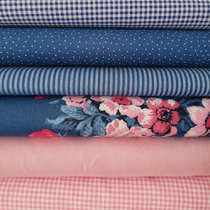 Könnte beinhalten: Ein Stapel aus sechs gefalteten Stoffen mit einem blau-weißen Vichy-Muster, einem blauen Stoff mit weißen Punkten, blau-weißen Streifen, einem dunkelblauen Blumenmuster mit rosa Blüten, einem einfarbigen hellrosa Stoff und einem rosa-weißen Vichy-Muster.