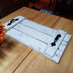 May include: White wooden serving tray with black metal handles. The tray is distressed and has a rustic look.