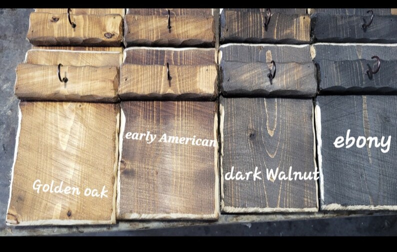 May include: Close-up of wooden blocks stained in different colors, including golden oak, early American, dark walnut, and ebony. Each block has a small metal hook.