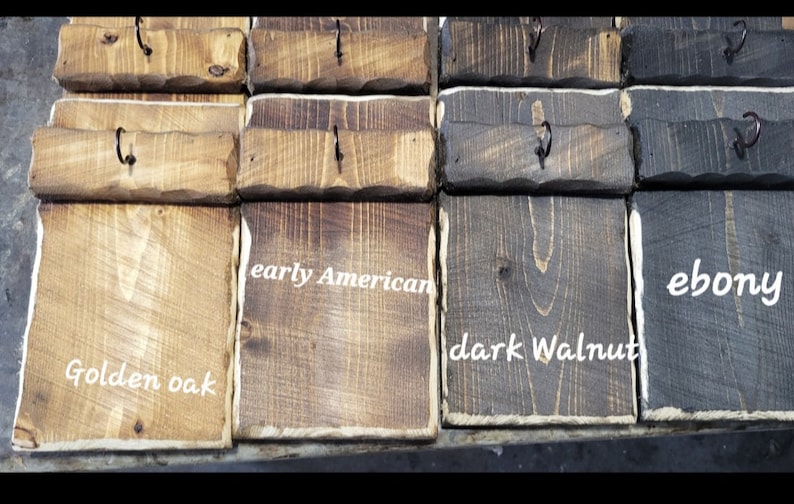May include: Close-up of wooden blocks stained in different colors, including golden oak, early American, dark walnut, and ebony. Each block has a small metal hook.