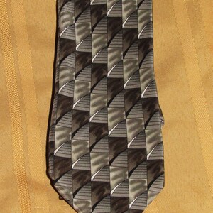 May include: A brown and gray patterned silk necktie. The pattern is a geometric design of squares and triangles.